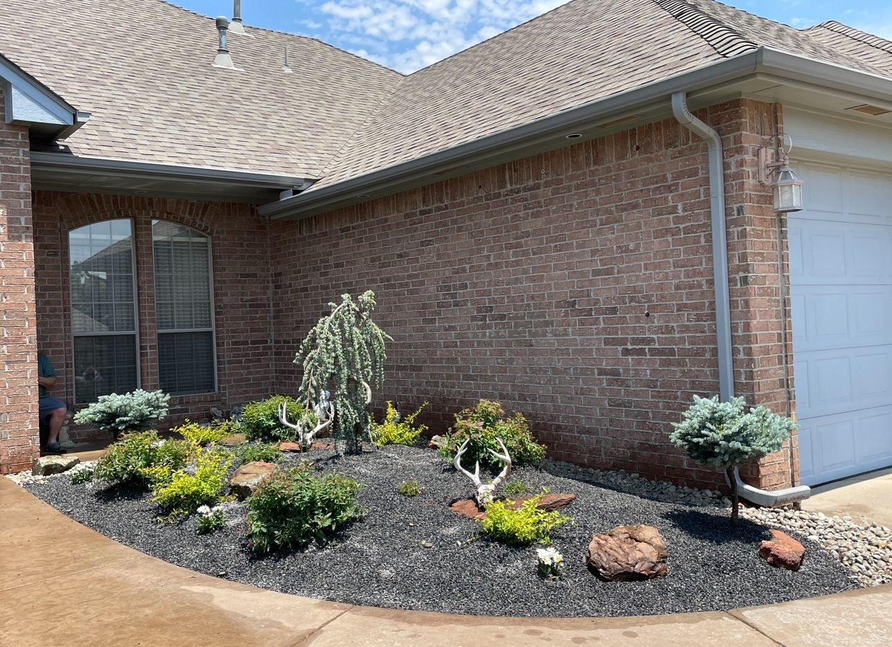 A brick house with a garden in front of it and a garage.