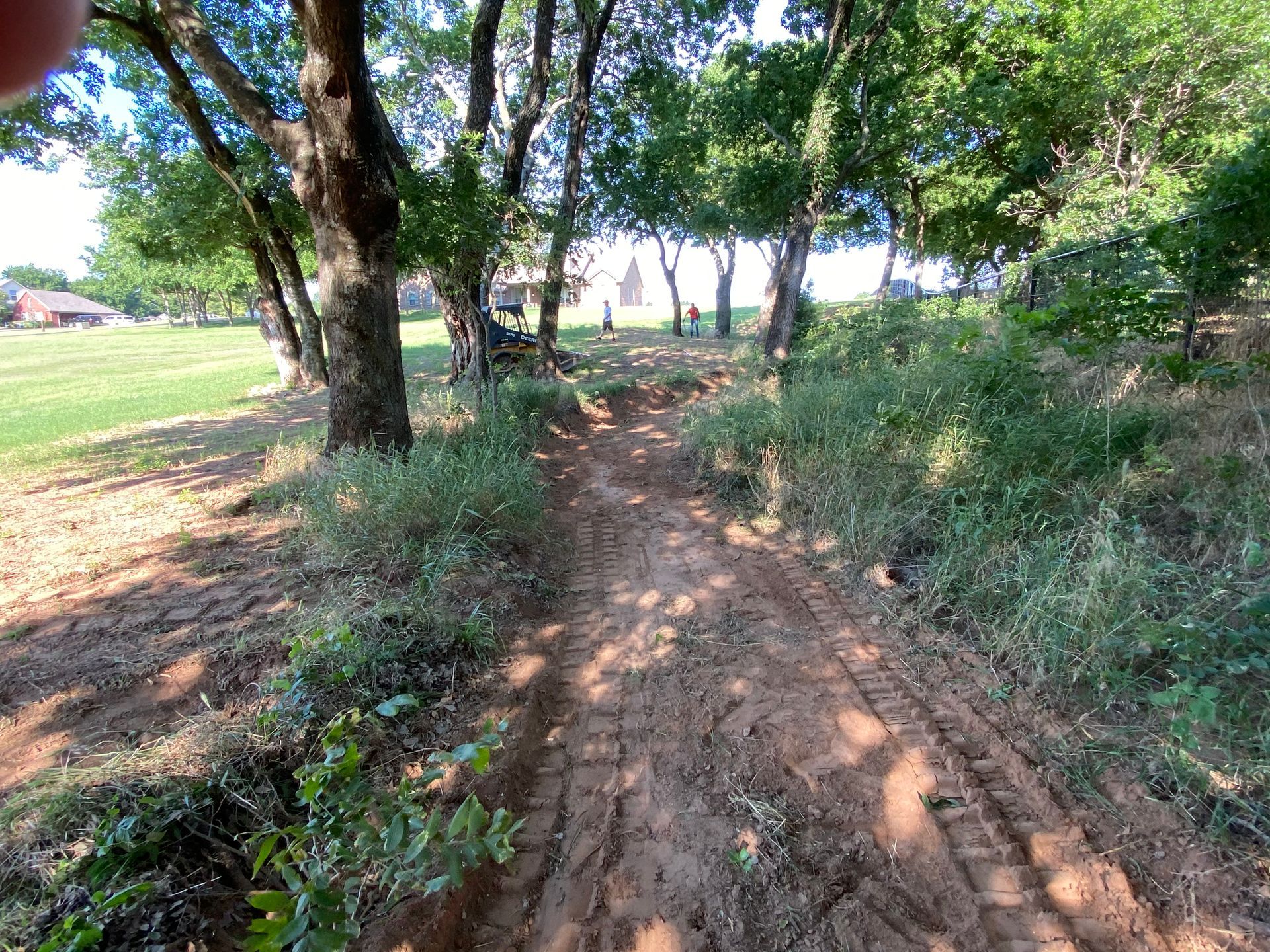 A dirt road going through a forest with trees on both sides.