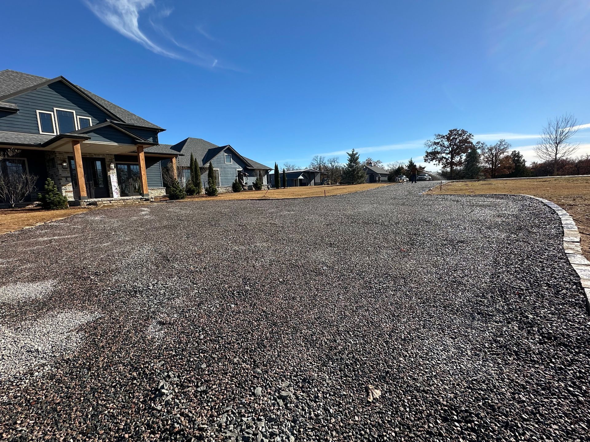 A gravel driveway leading to a house on a sunny day.