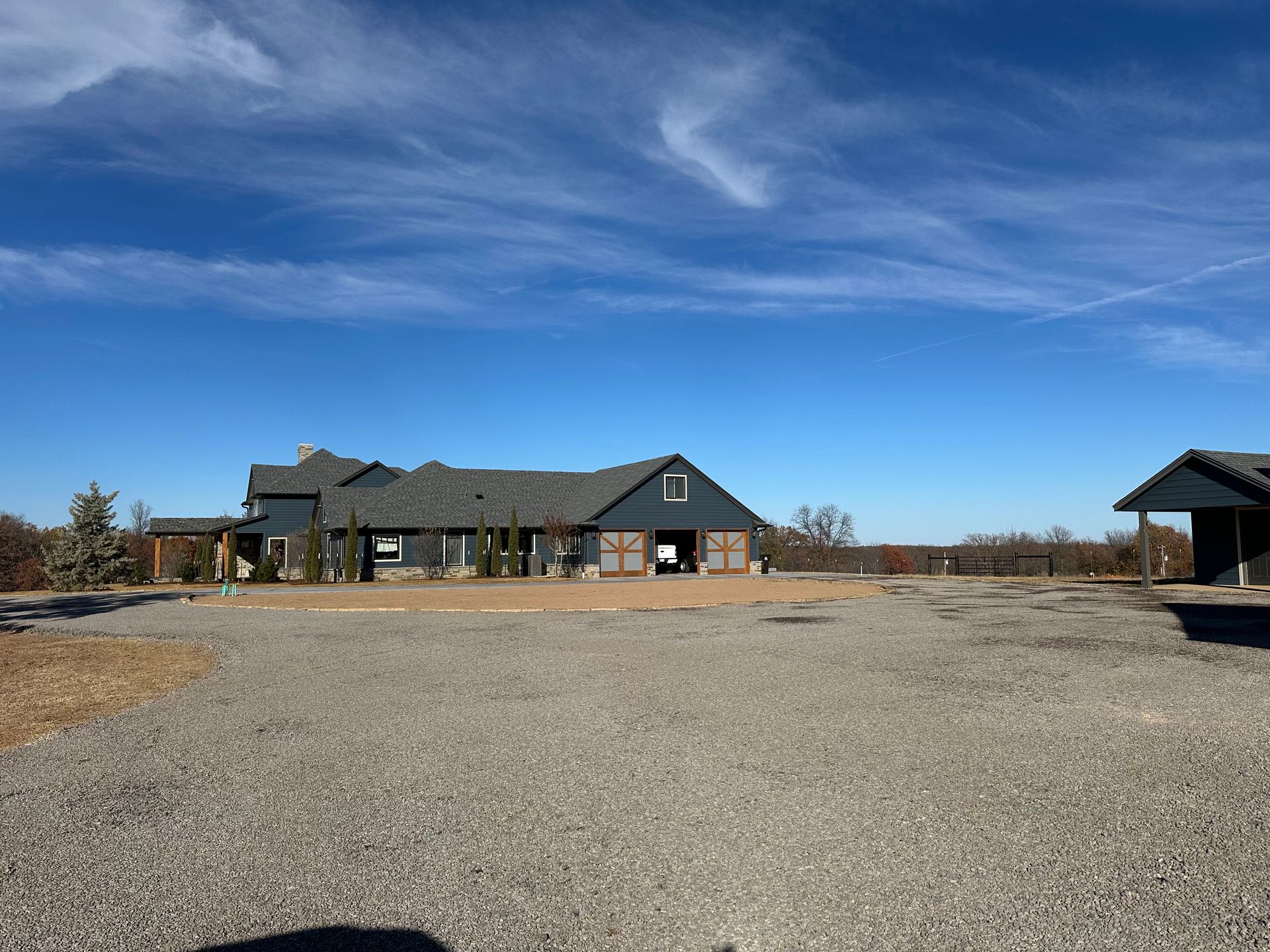 A large house is sitting on top of a gravel lot.