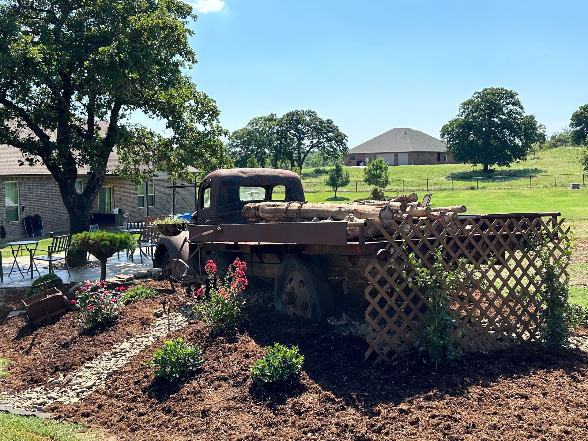 An old rusty truck is parked in a garden in front of a house.