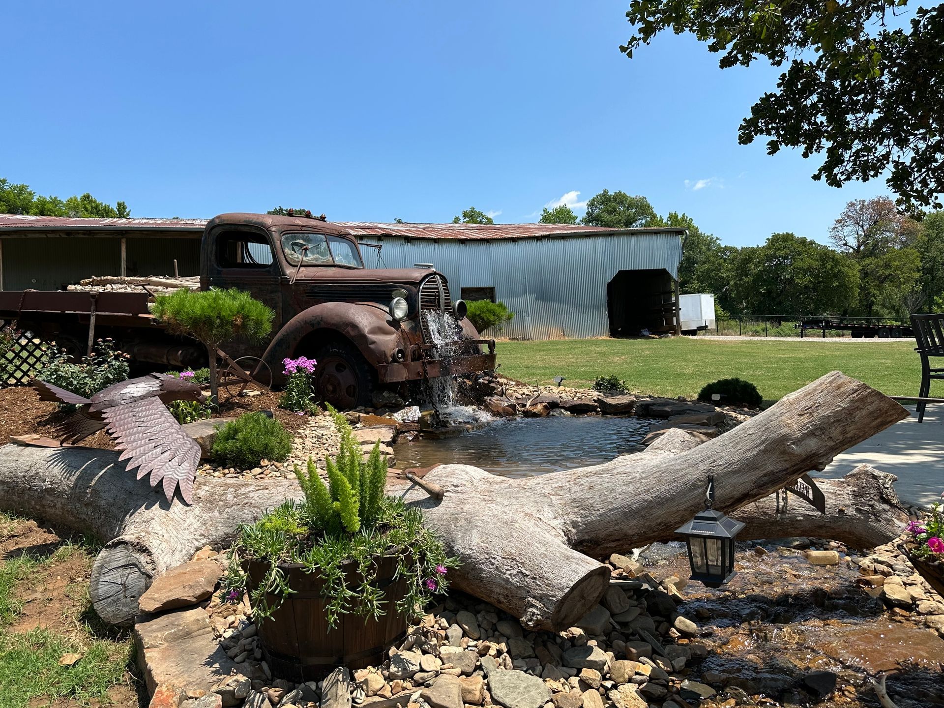 An old truck is parked in a yard next to a pond.