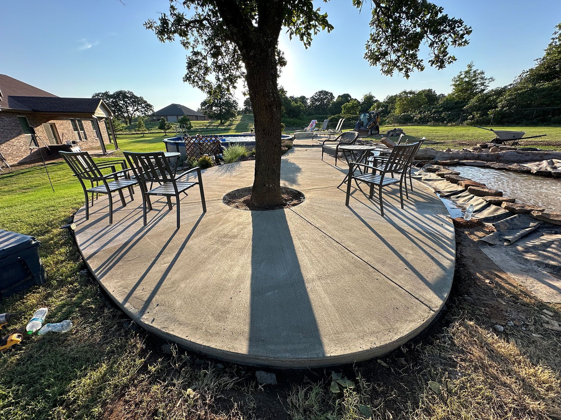 a patio with chairs and a tree in the middle