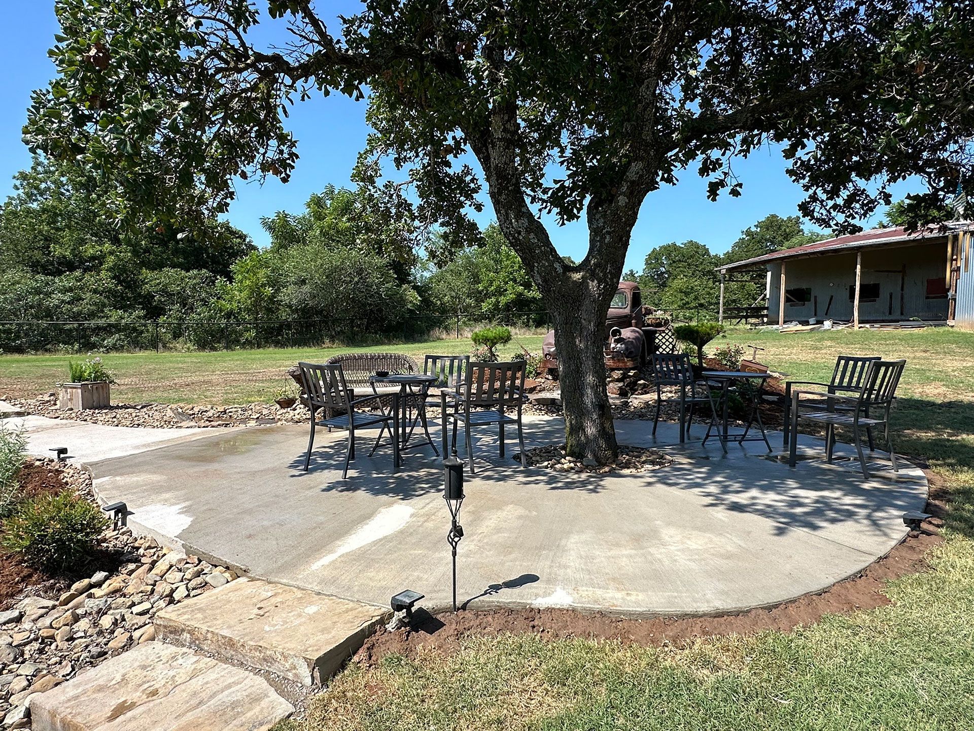 a patio with a table and chairs under a tree