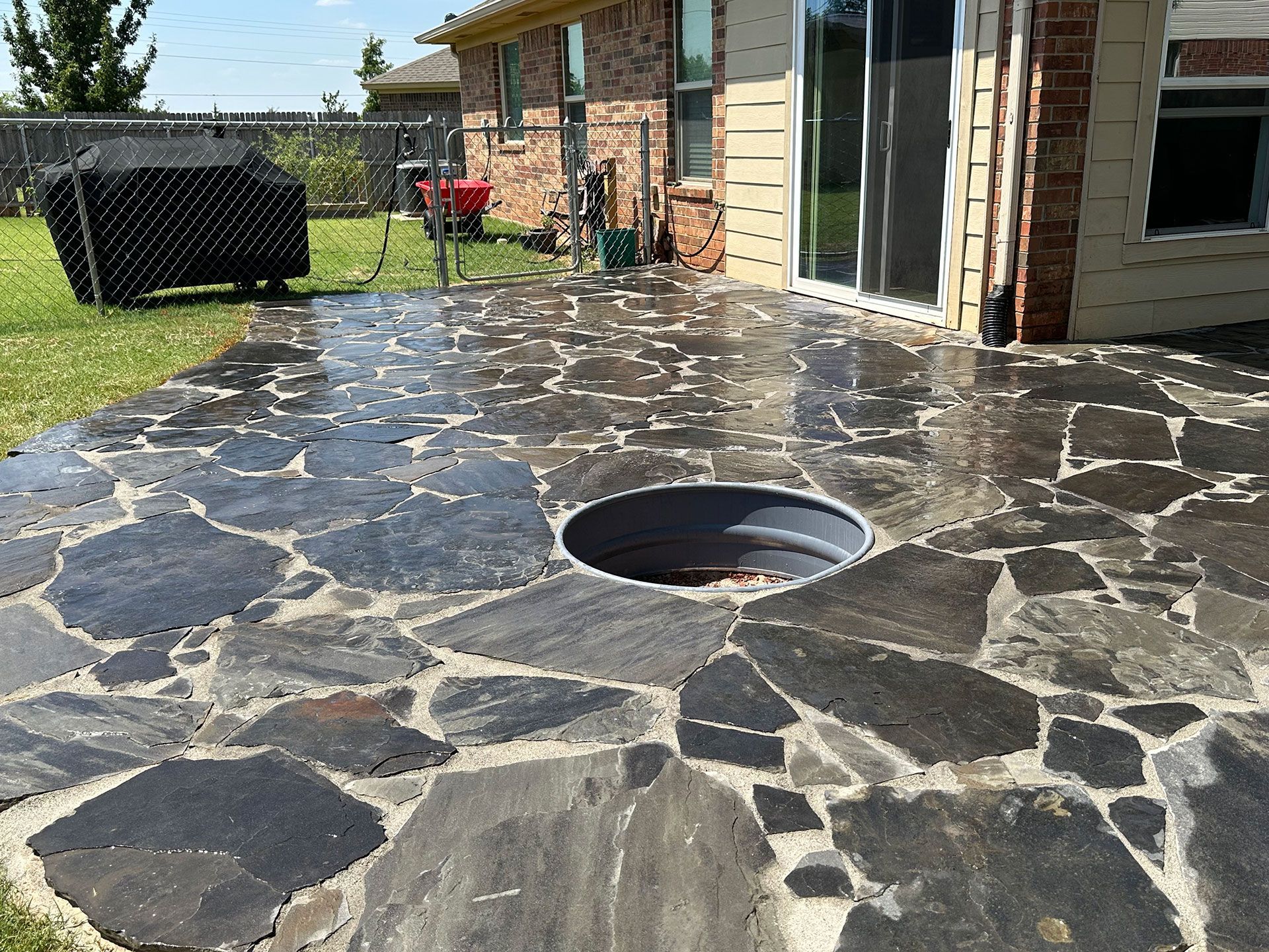 a stone patio with a fire pit in the middle of it
