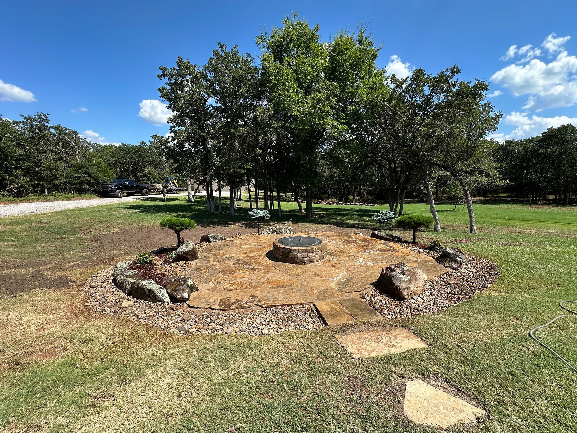 a fire pit in the middle of a grassy field surrounded by trees