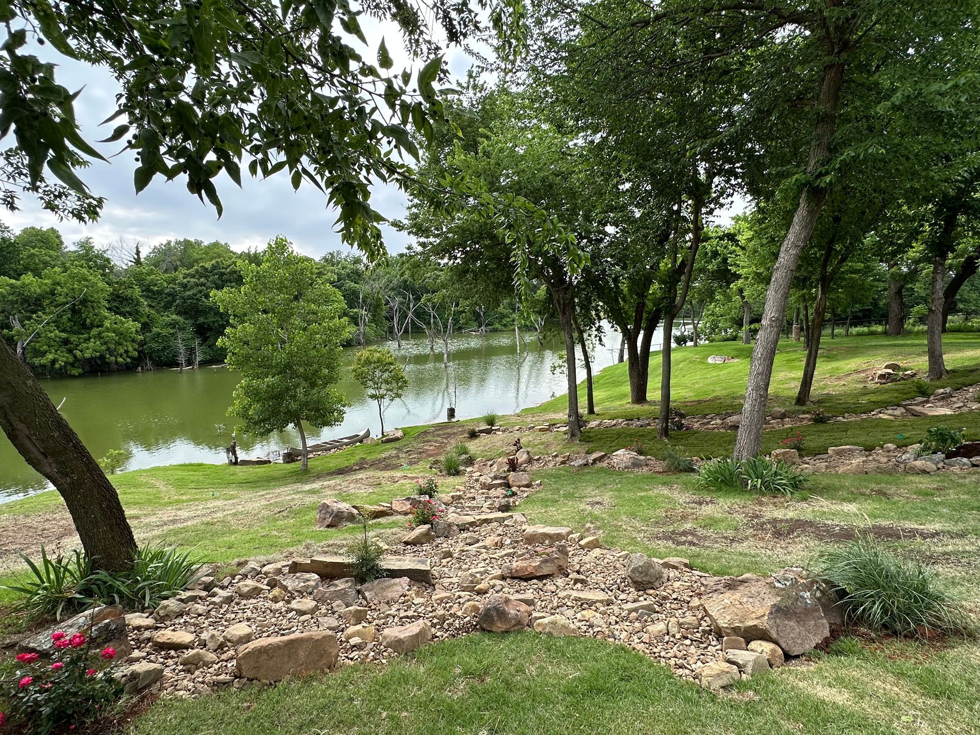 A path leading to a lake surrounded by trees and rocks.