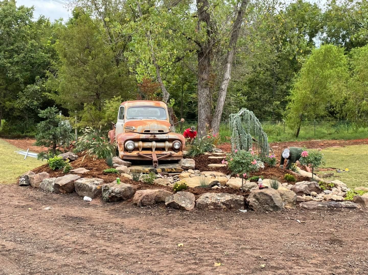 An old truck is parked in the middle of a rock garden.