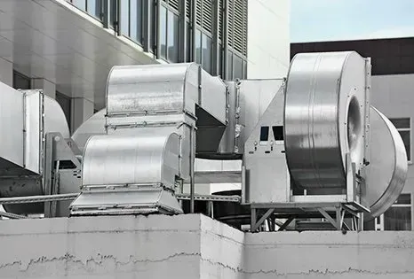 Silver HVAC ductwork and fans on a building rooftop.