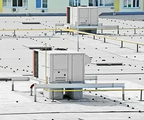 HVAC units on a flat rooftop with yellow safety railings.