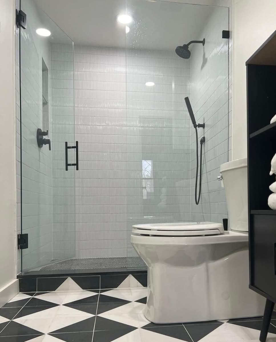 Bathroom with glass shower, white subway tile, black fixtures, and black and white checkered floor