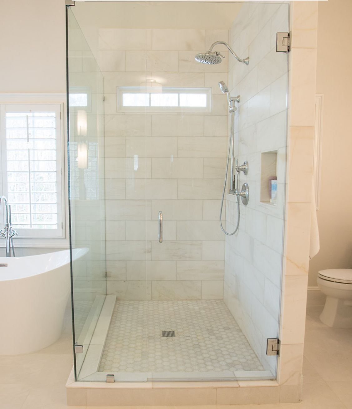 Glass shower with white tile walls and floor