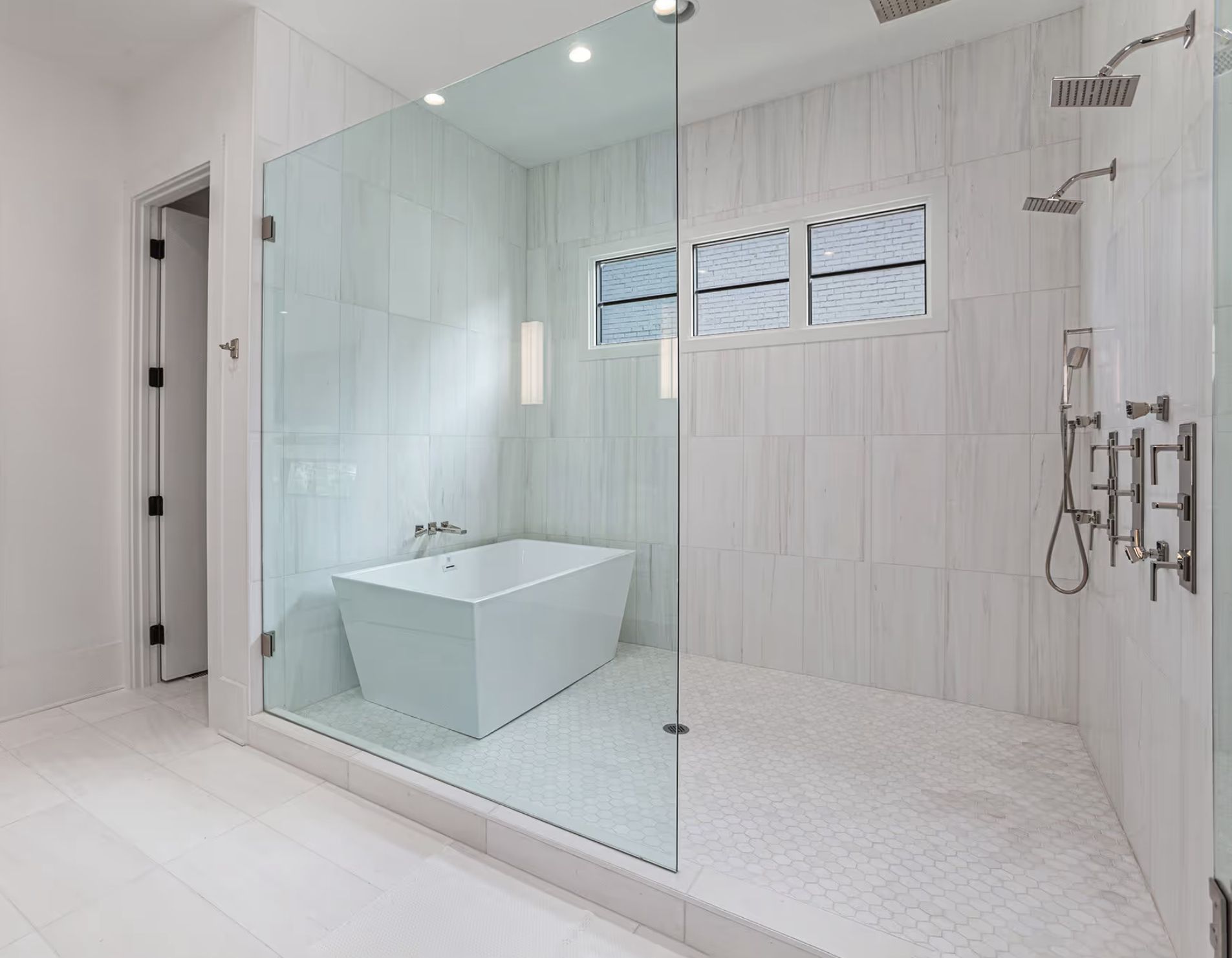 Modern white bathroom with glass shower, bathtub, and two windows