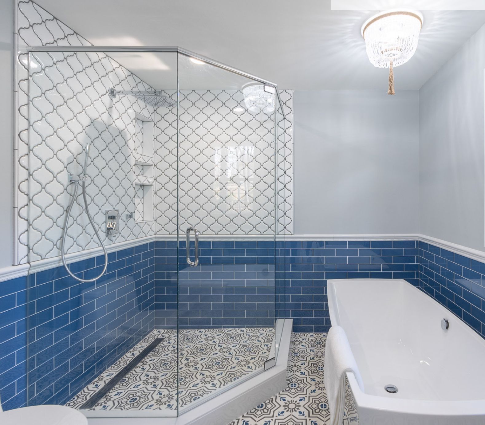 Blue and white tiled bathroom with a glass shower and a white bathtub