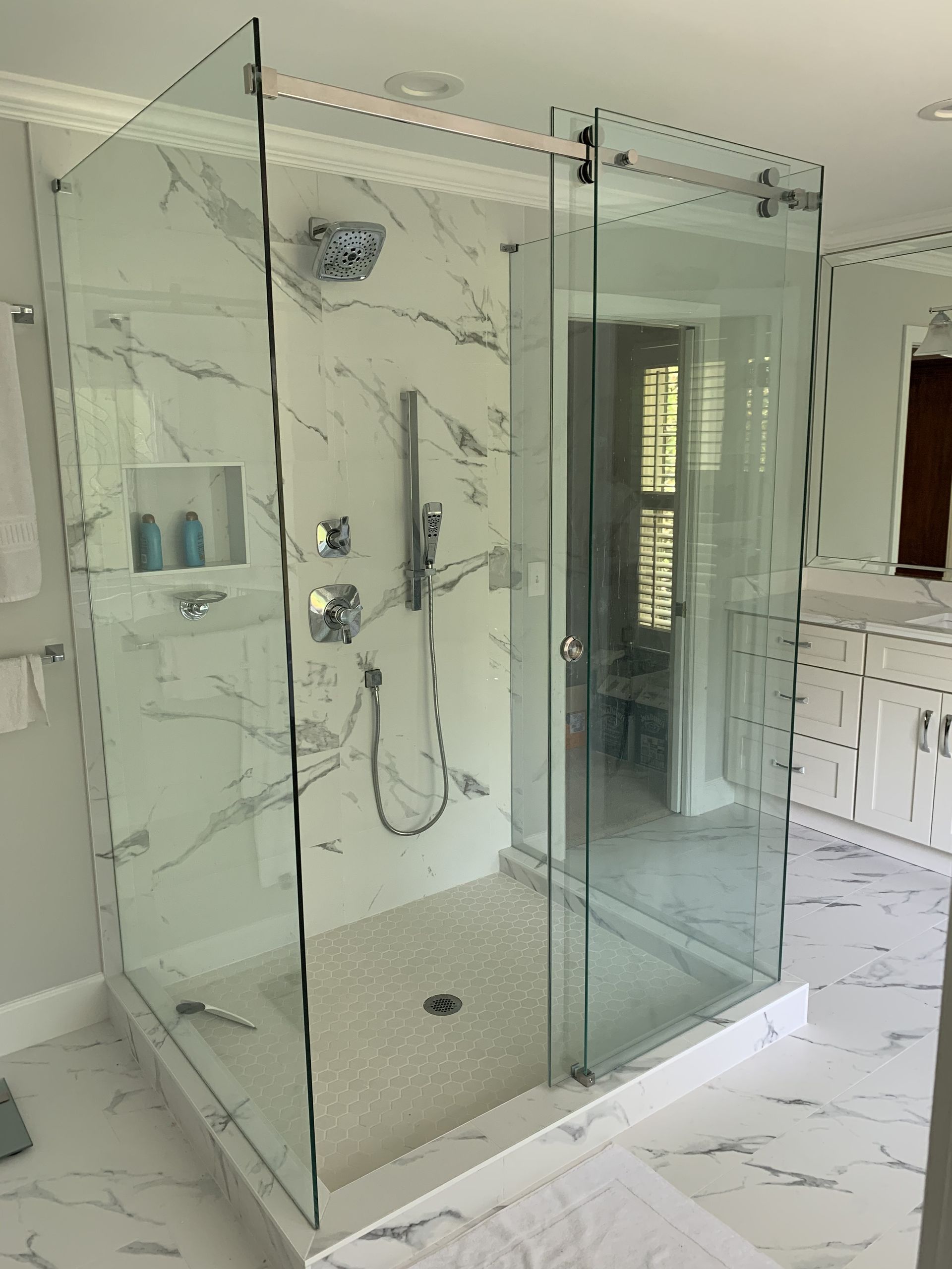 Glass-enclosed shower in a marble-tiled bathroom