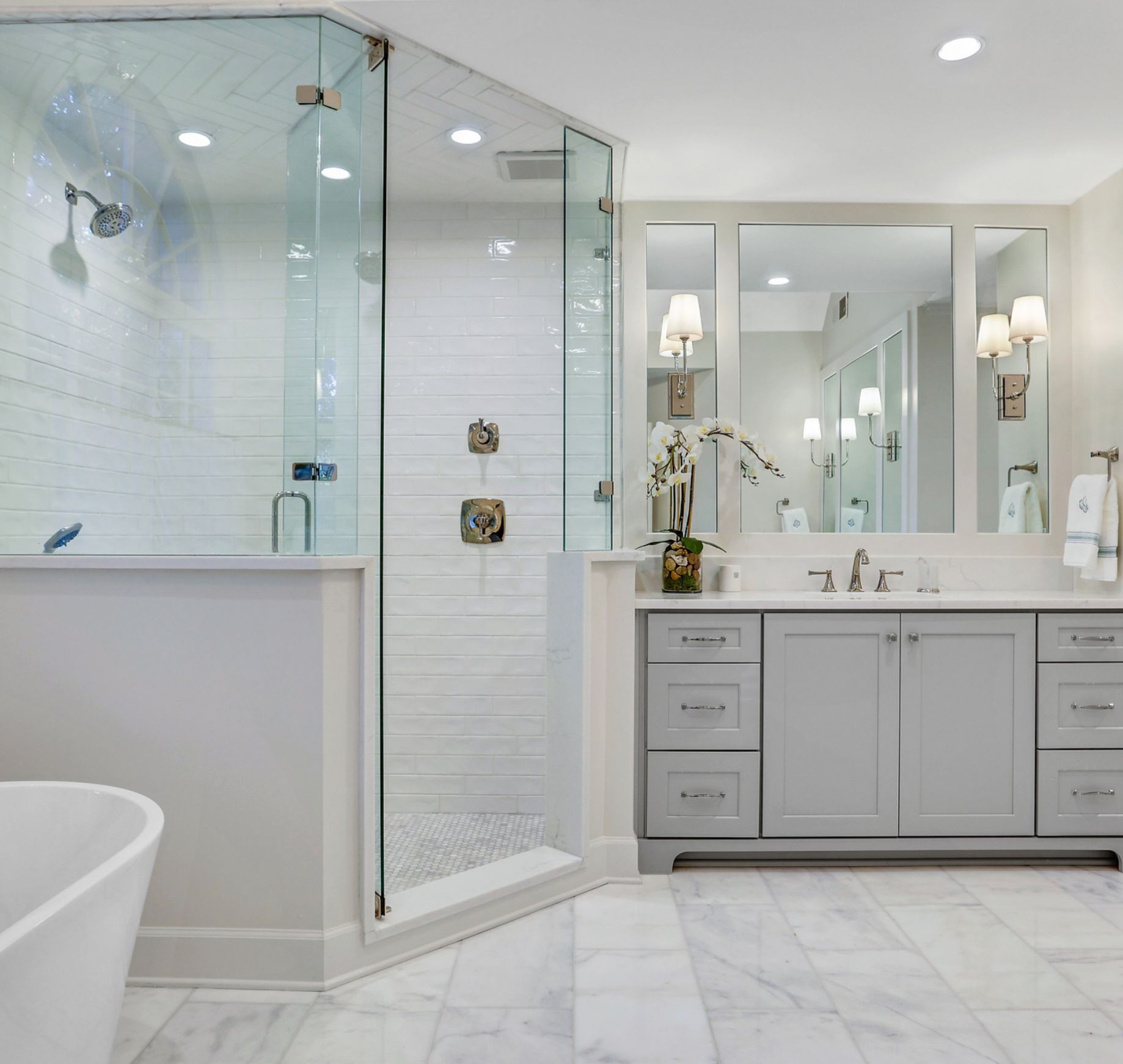 Modern bathroom with a glass shower, gray vanity, and white tile