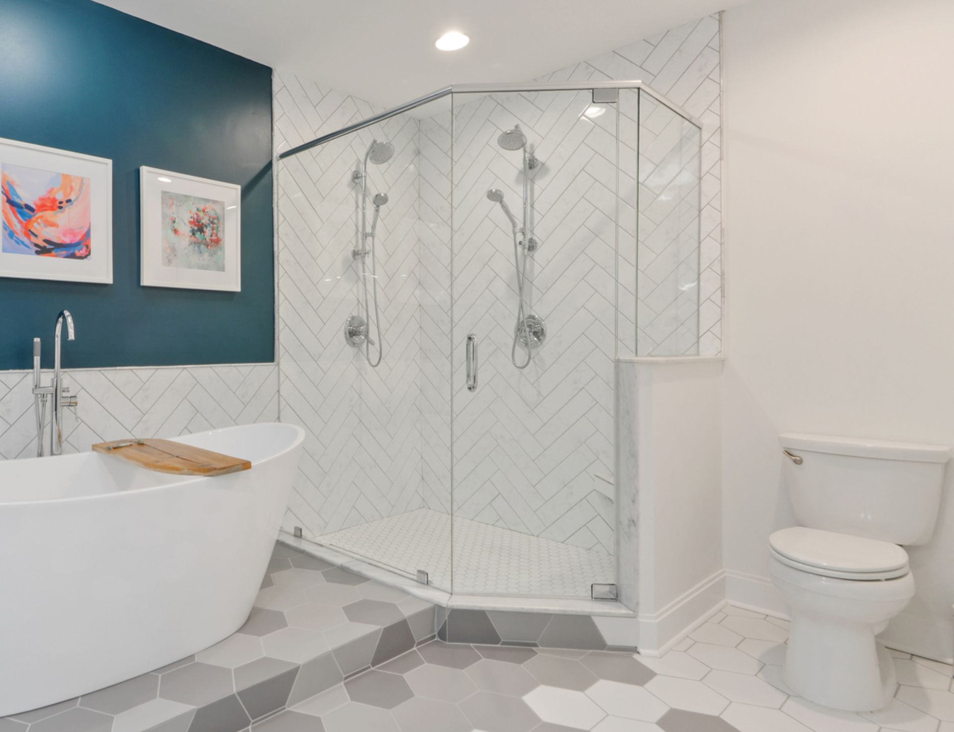 Modern bathroom with blue accent wall, white tub, and glass shower