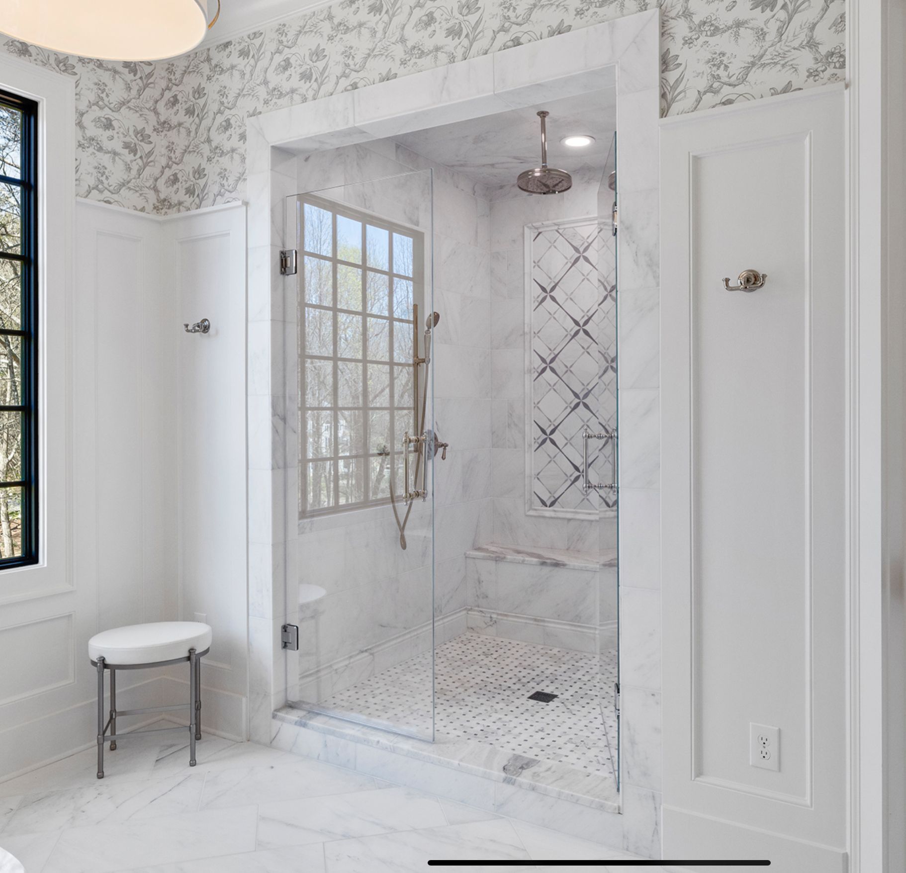 Elegant white bathroom with marble shower, glass door, and floral wallpaper