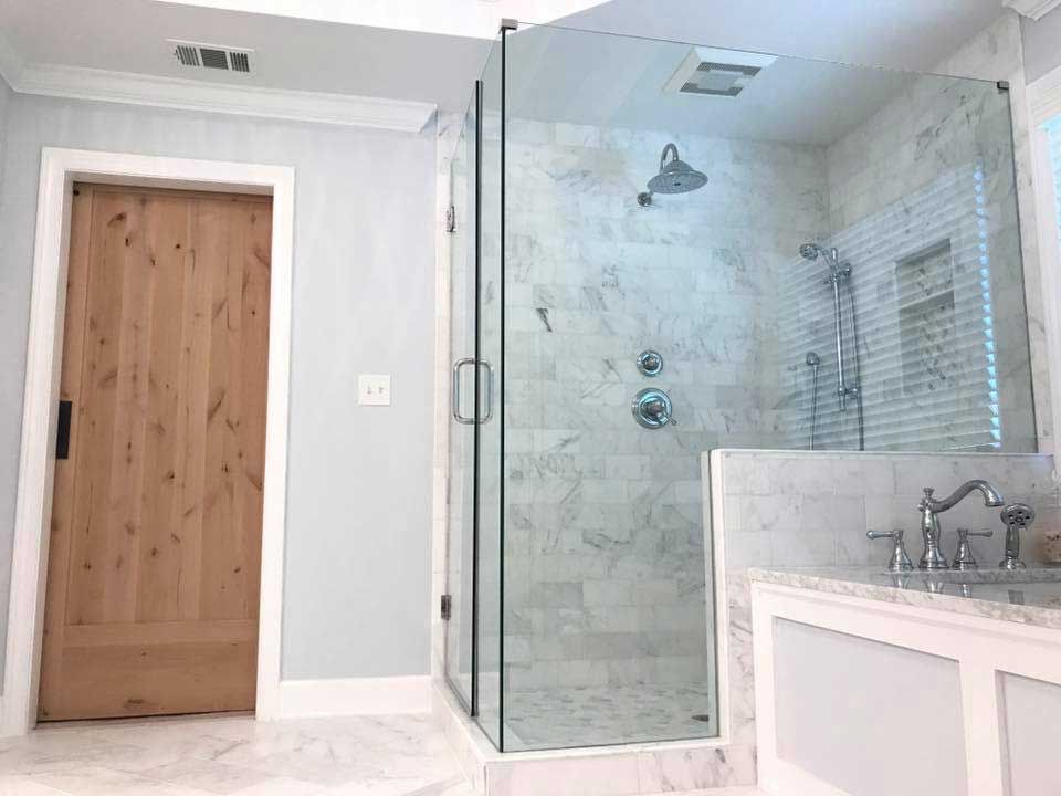 A bathroom with a walk in shower and a wooden door.