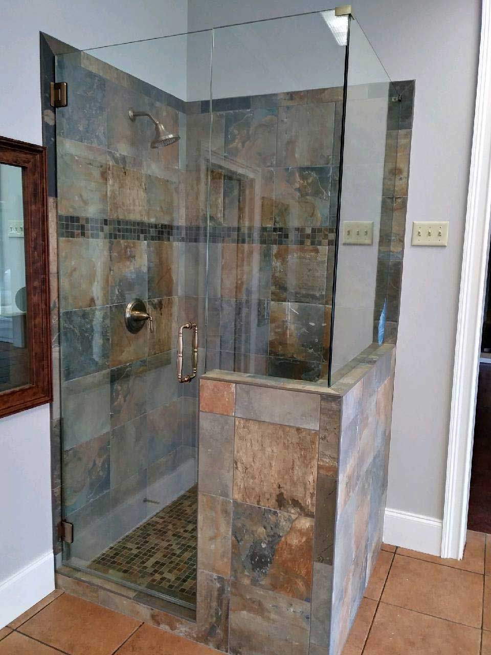 A bathroom with a walk in shower with a glass door.