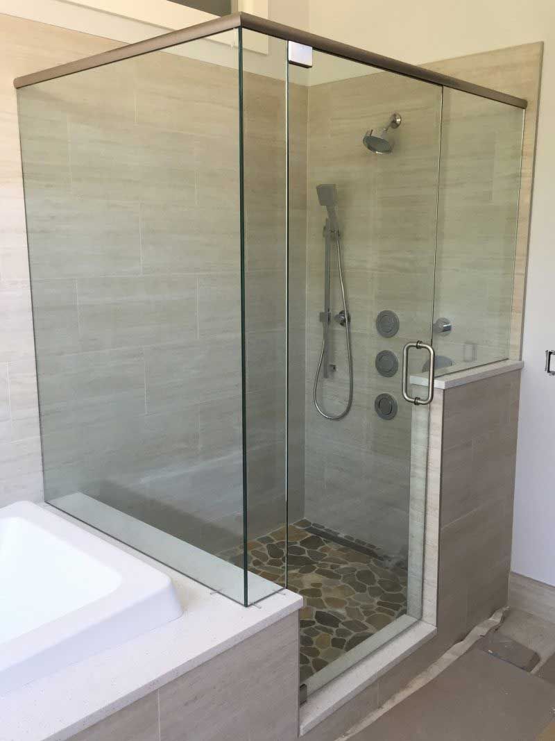 A bathroom with a glass shower door and a bathtub.