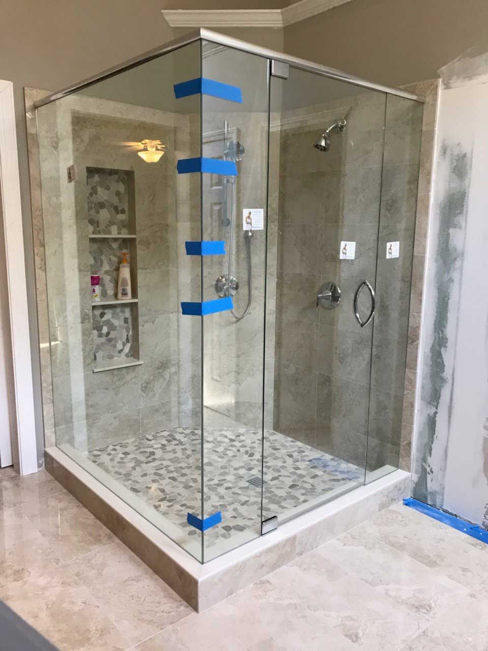 A bathroom with a walk in shower with a glass door.
