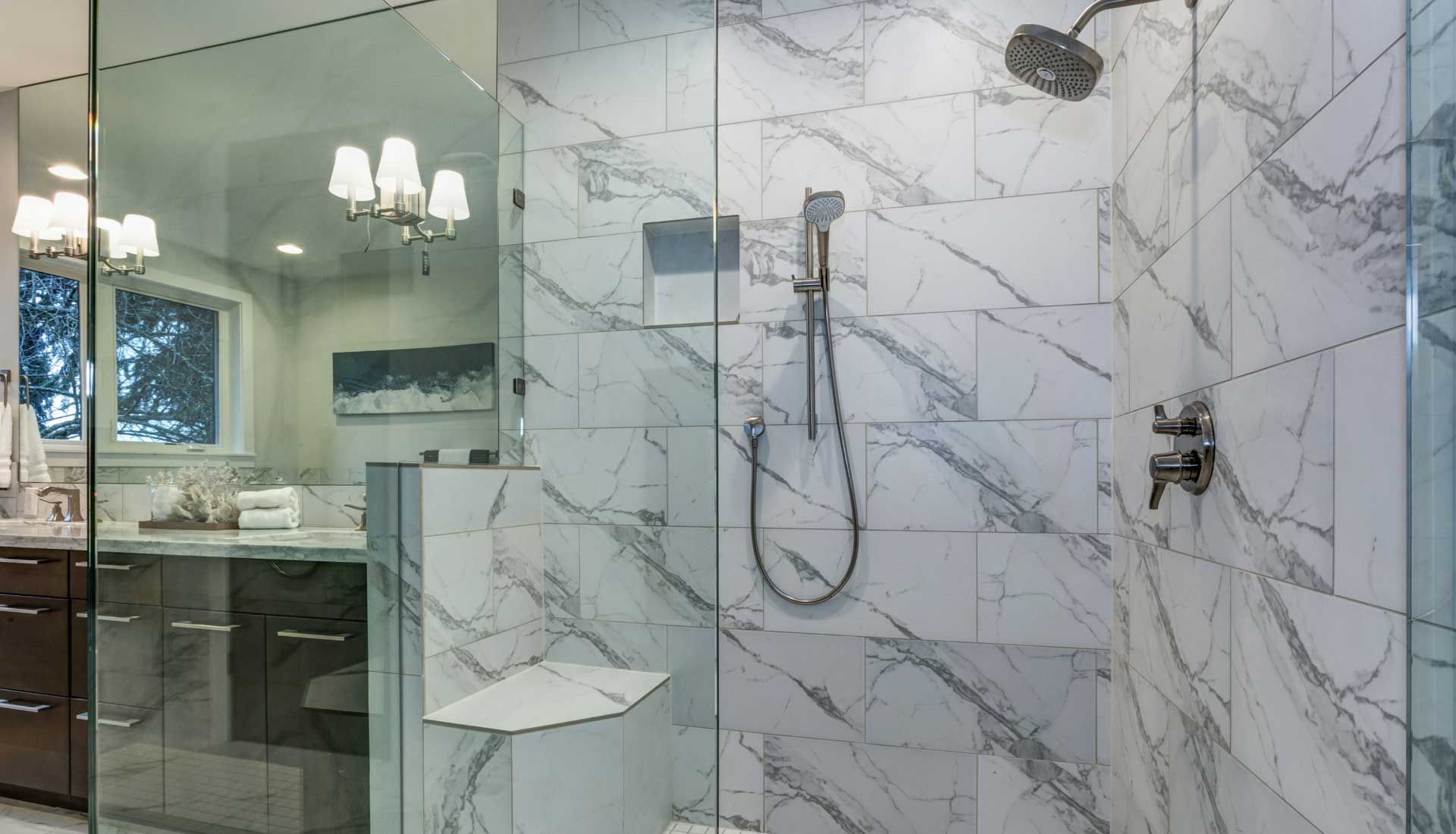 A bathroom with marble tiles and a walk in shower with a glass door.