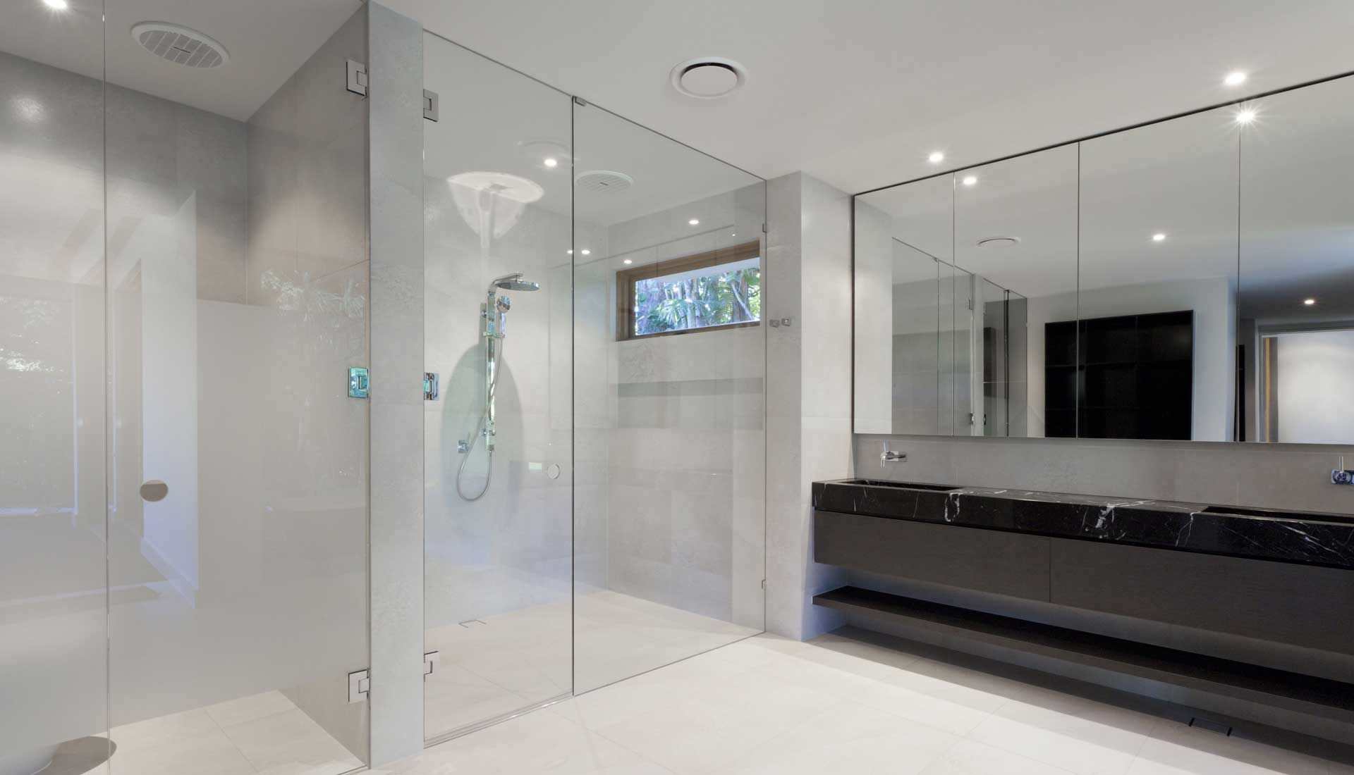 A bathroom with a walk in shower and two sinks.