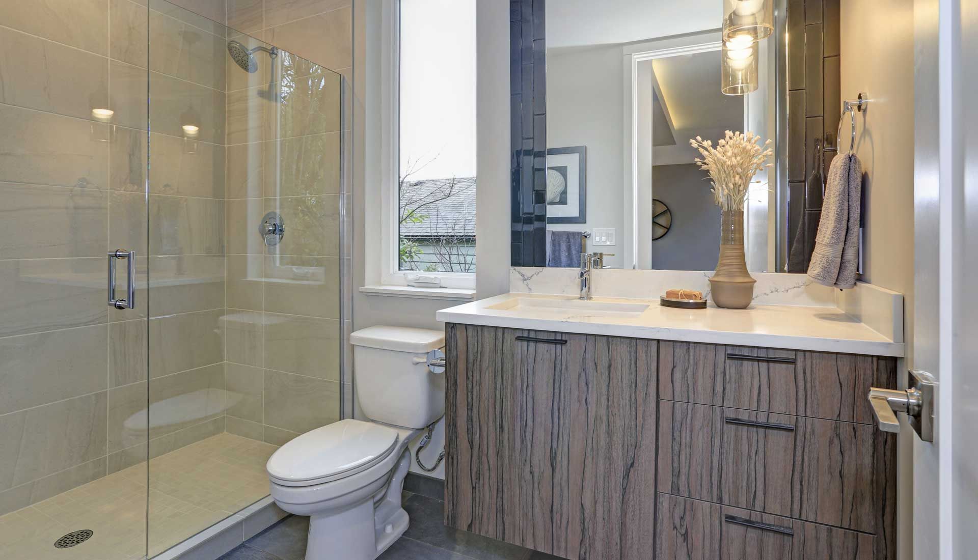 A bathroom with a toilet , sink , shower and mirror.