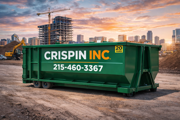 A light grey dump truck tilting a large, rectangular green metal dumpster onto a dirt surface.