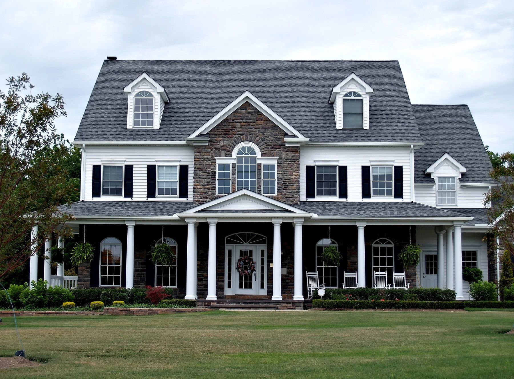 A large white house with a gray roof and black shutters