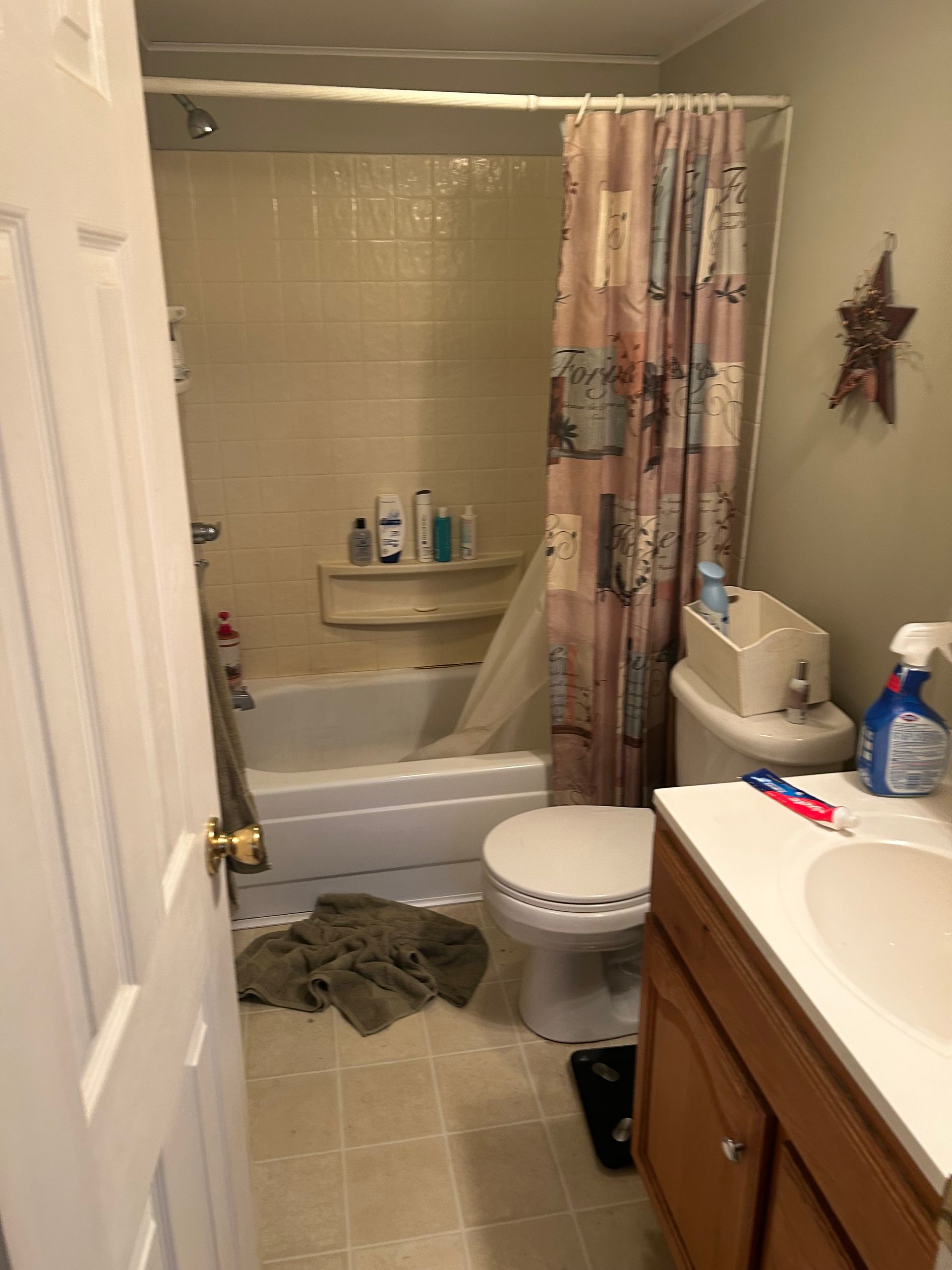 Bathroom with shower/tub, toilet, sink, and closed door. Beige and brown tones.