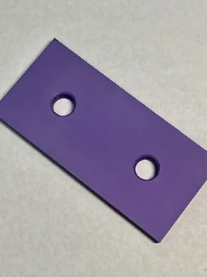A purple piece of plastic with two holes in it is sitting on a table.