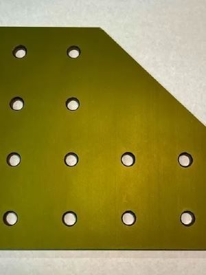 A green metal plate with holes in it is sitting on a table.