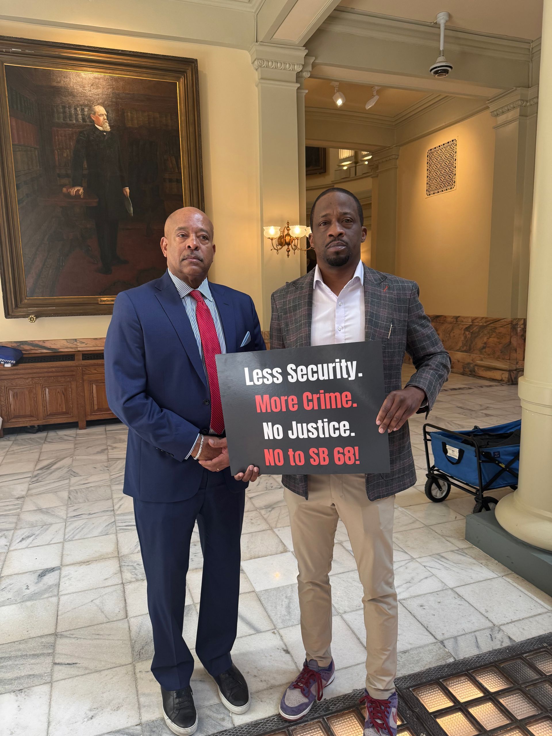 Two men standing next to each other holding a sign.