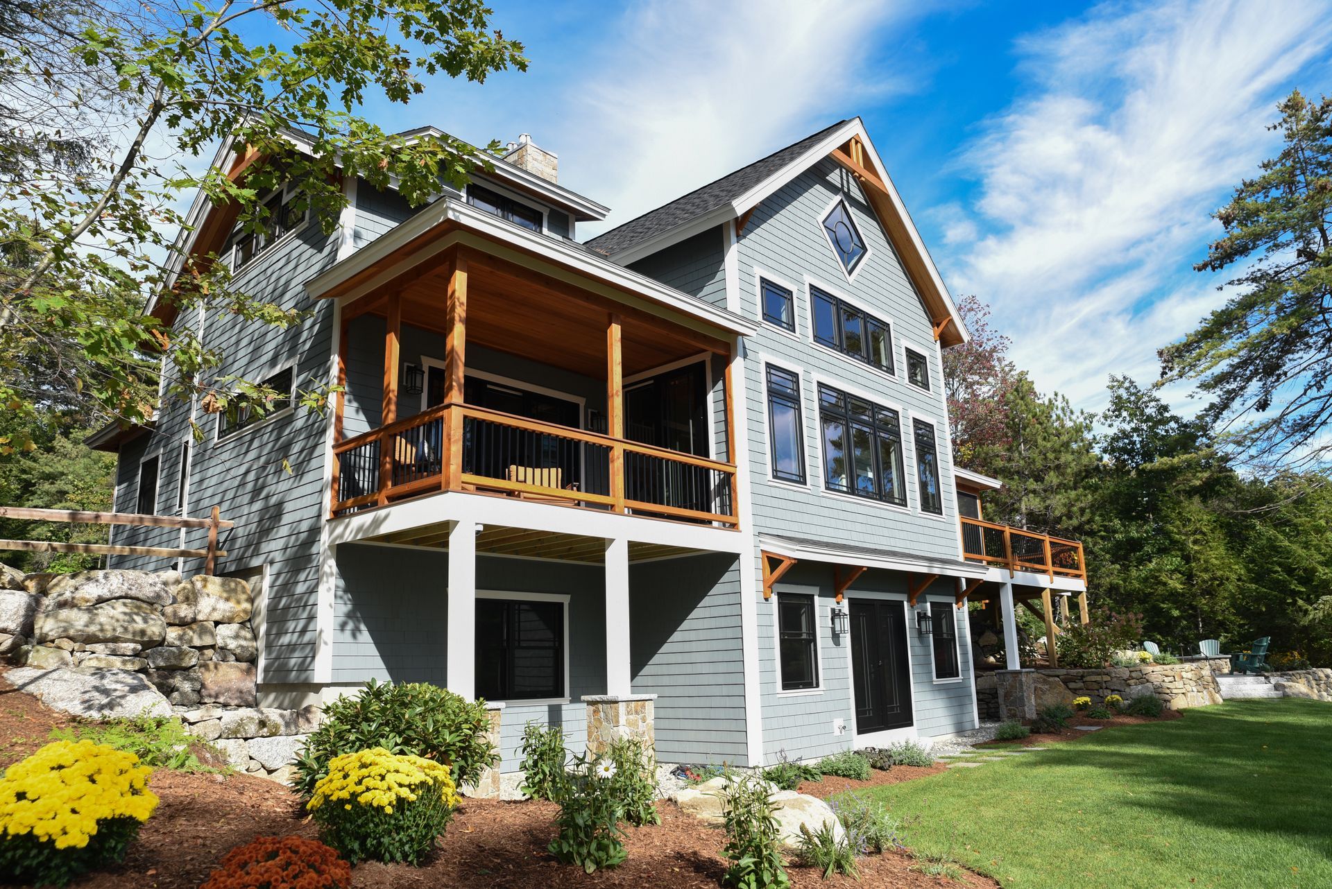 A large house with a large porch is surrounded by trees and bushes.