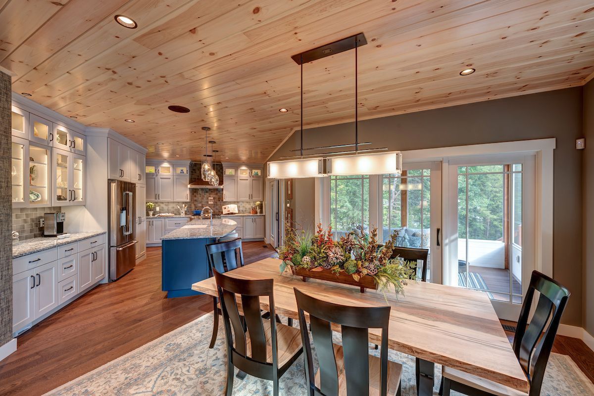 A dining room with a table and chairs and a wooden ceiling.