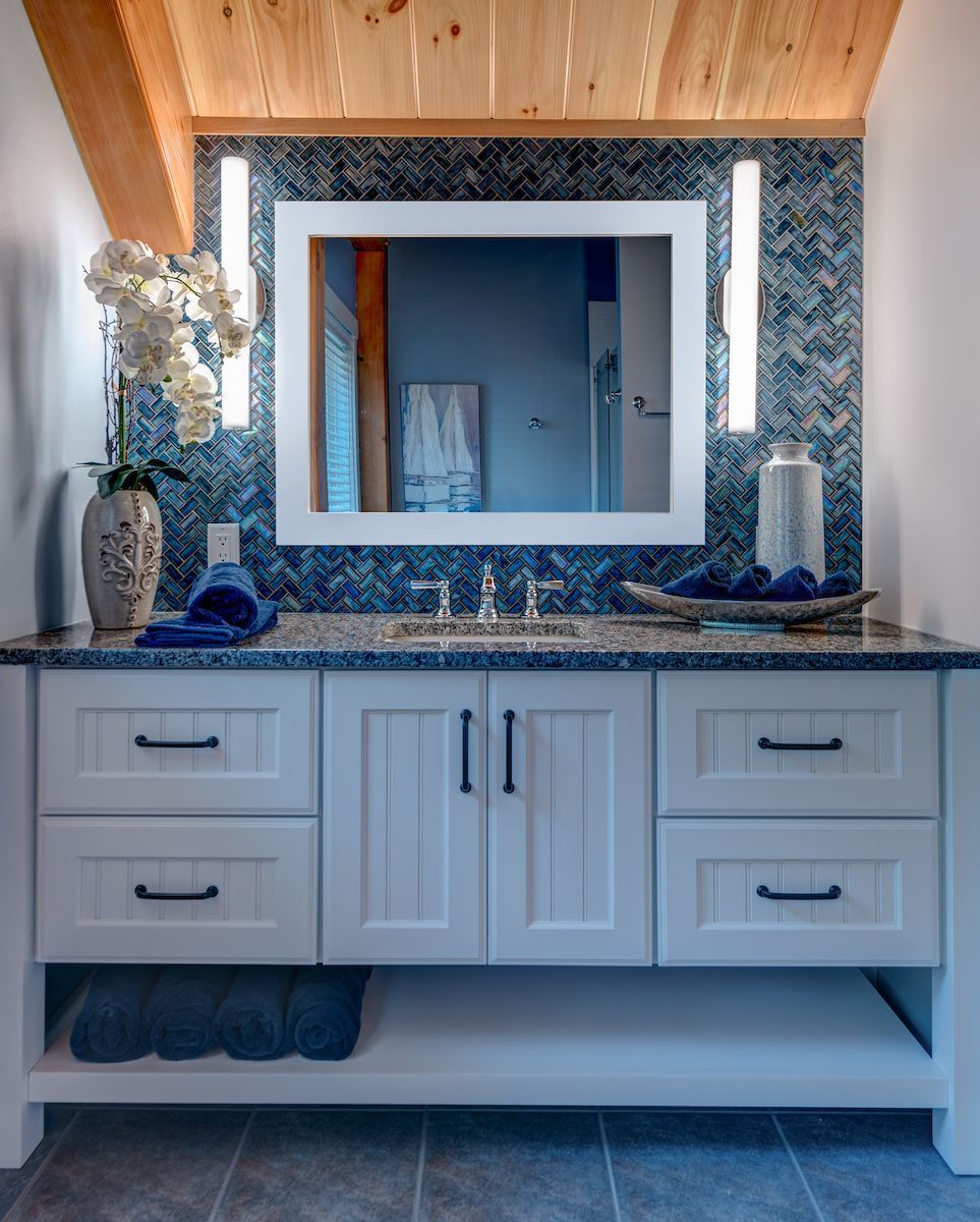A bathroom with white cabinets and a large mirror