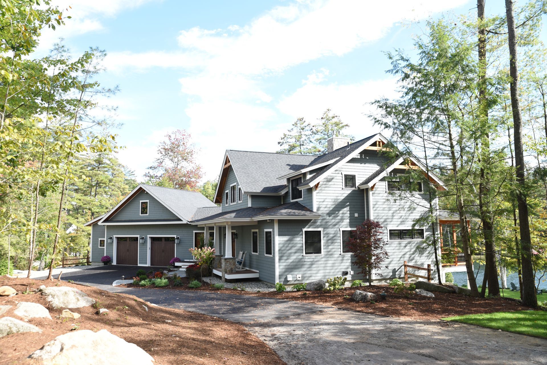 A large house is surrounded by trees and a gravel driveway.