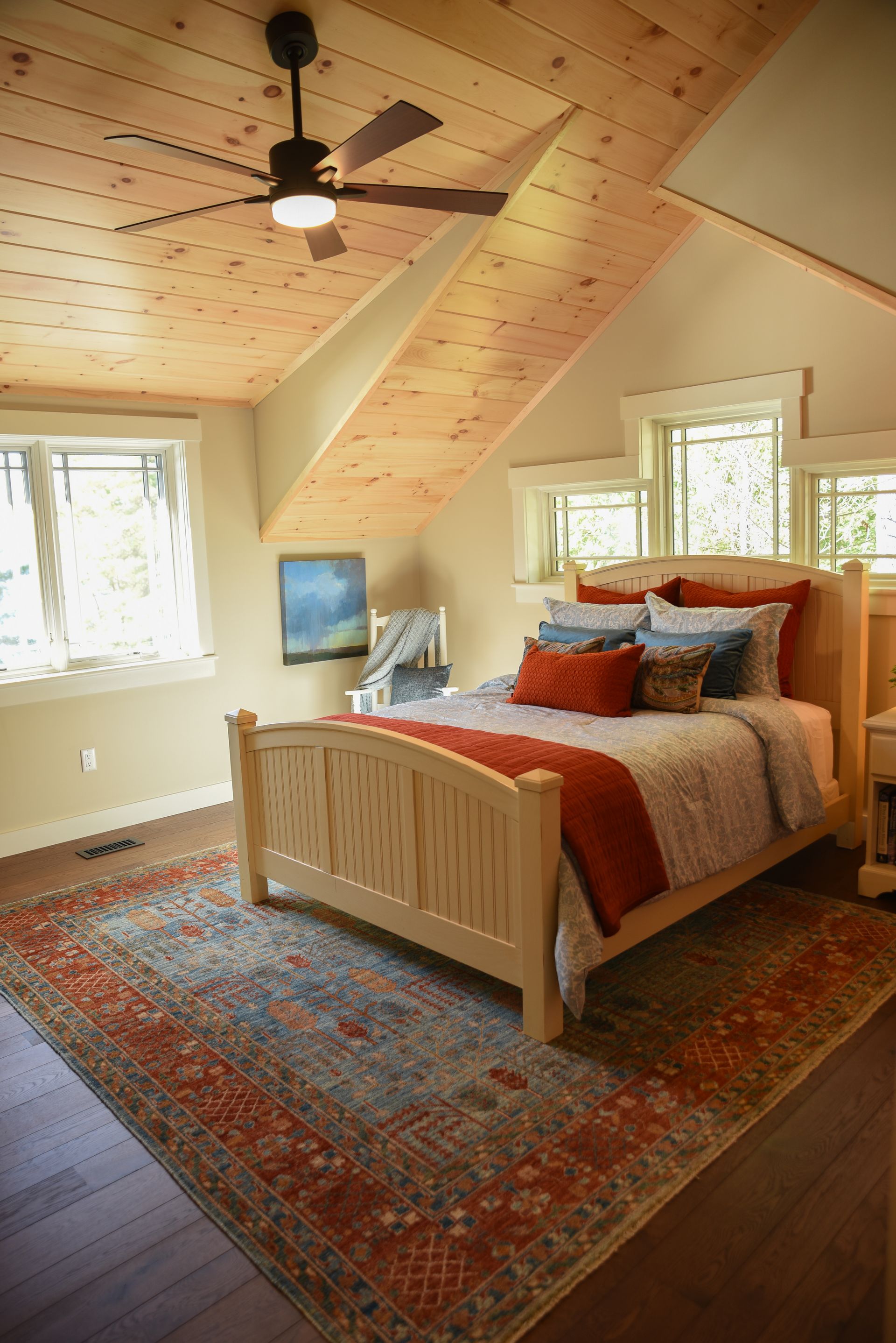 A bedroom with a bed , rug and ceiling fan.