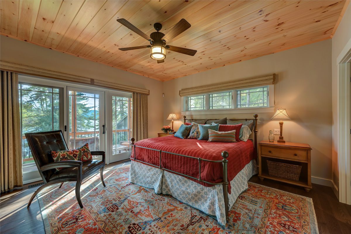 A bedroom with a bed , chair , nightstand and ceiling fan.