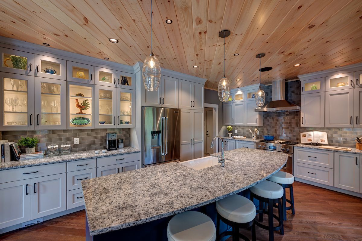 A kitchen with white cabinets , granite counter tops , stainless steel appliances and a large island.