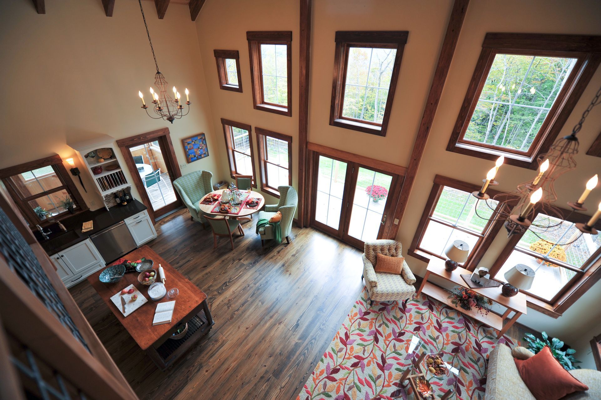 High-angle view of a cabin interior with large windows, dining area, and living space with wood flooring.