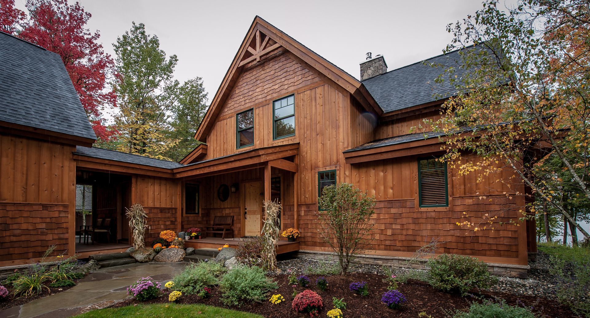 Wooden house with dark roof and landscaping in front.