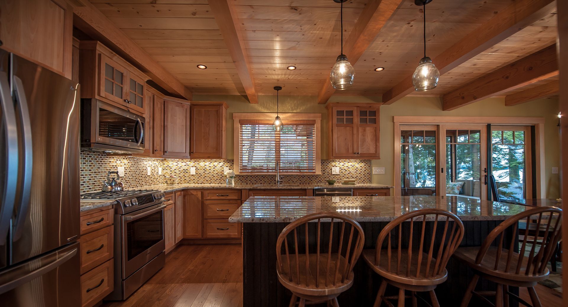 Kitchen with wood cabinets, island, and ceiling beams; stainless steel appliances.