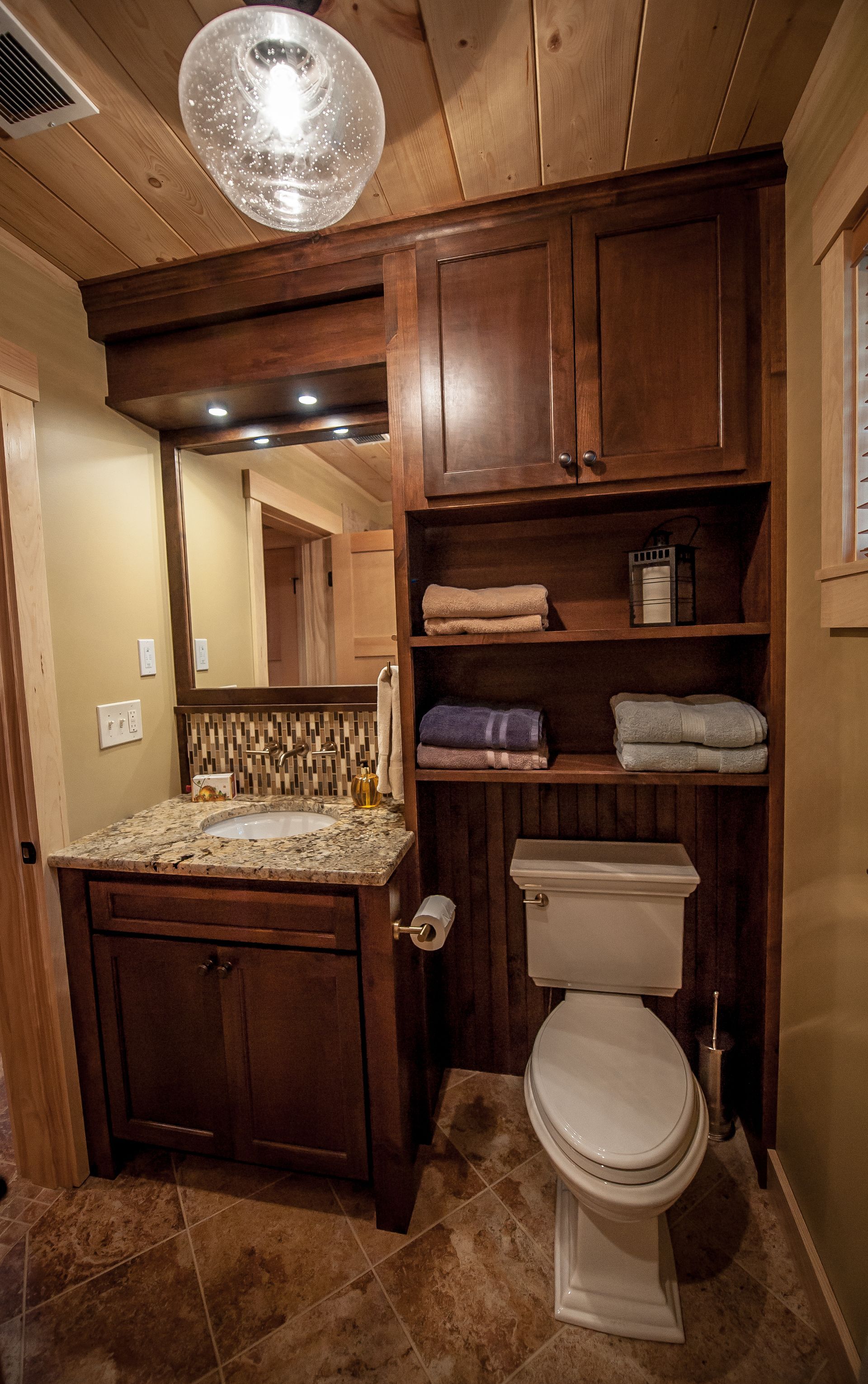 Bathroom with dark wood cabinetry, tan walls, and a decorative tile backsplash.