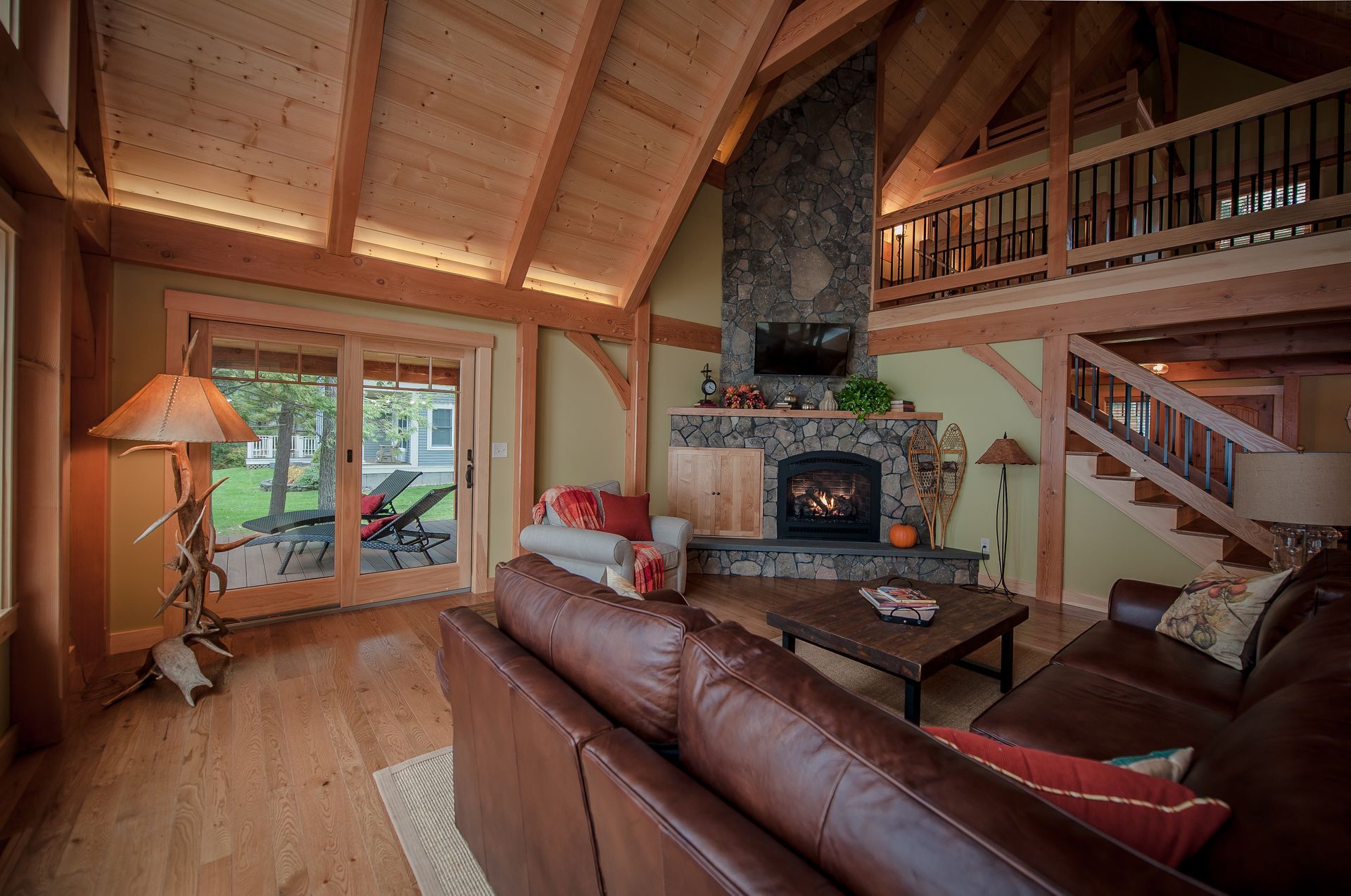 Cozy living room with fireplace, leather sofa, wood beams, and a sliding door leading to the backyard.