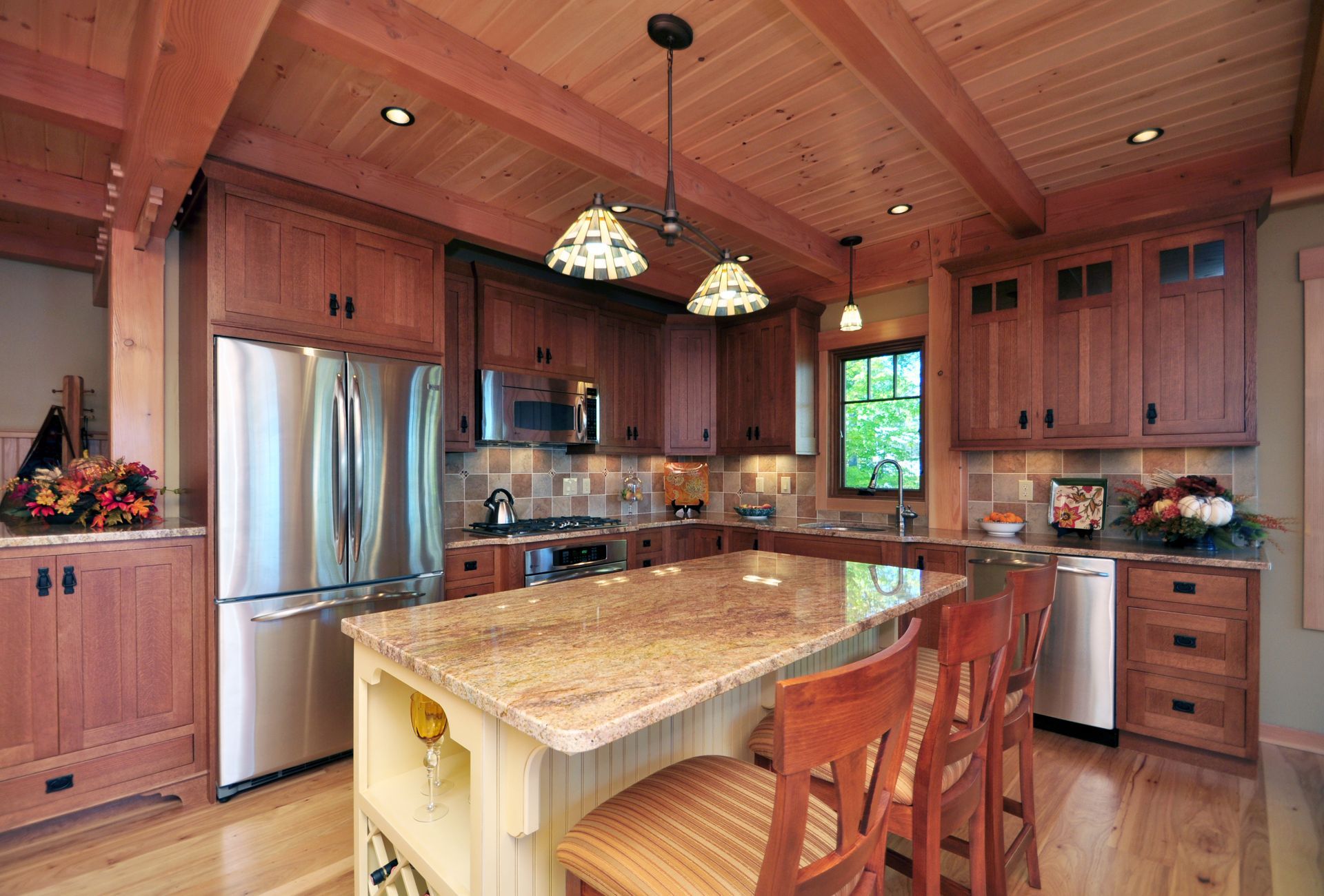 Kitchen with wooden cabinets, stainless steel appliances, and a granite island with bar stools.