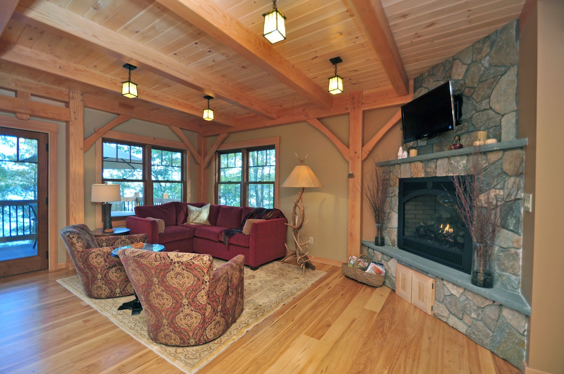 Cozy living room with stone fireplace, red sofa, and exposed wooden beams.