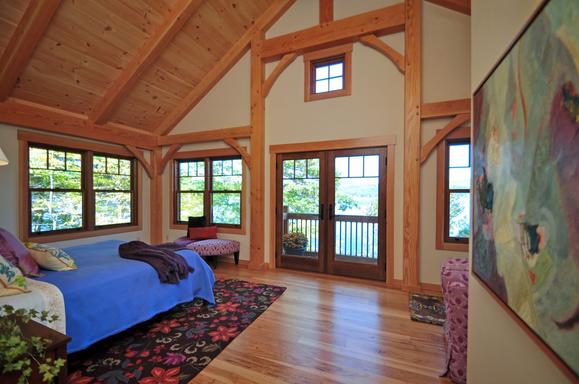 Bedroom with wood beams, blue bed, and a view through double doors.